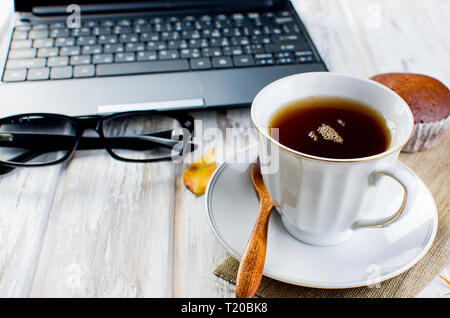 Herbst noch leben. Tea Party Herbst Tag Tasse Kaffee, Kuchen, Nüsse, Blätter, Blumen, Brille und Laptop. Kopieren Sie Platz. Stockfoto