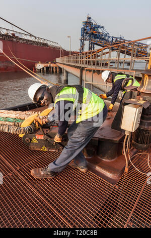 Port Operations für den Transport von Eisenerz. Dolphin Anlegestelle Anlegestelle mit rigger mit Quick release Seil Haken als Schiff setzt Segel Stockfoto