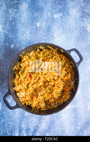 Afrikanische jollof Reis in einem dunklen Gefäß gekocht. Ansicht von oben afrikanischen Reis essen. Gekochte Afrikanische jollof Reis auf einem grauen Hintergrund. Stockfoto