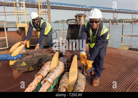 Port Operations für den Transport von Eisenerz. Dolphin Anlegestelle Anlegestelle mit rigger mit Quick release Seil Haken als Schiff setzt Segel Stockfoto