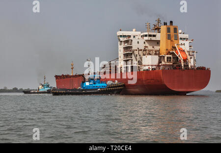 Port Operations für den Transport von Eisenerz. Schlepper manövrieren und drehen das Umladen Schiff vor dem Andocken und Beladung zu erz bei Steg Stockfoto