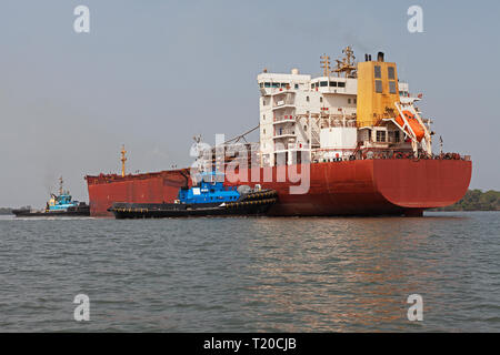 Port Operations für den Transport von Eisenerz. Schlepper manövrieren und drehen das Umladen Schiff vor dem Andocken und Beladung zu erz bei Steg Stockfoto