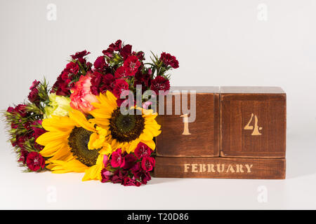 Happy Valentine's Day vintage Holz- Ewiger Kalender für Februar 14 isoliert auf weißem Hintergrund und ein Bündel von verschiedenen Blumen Stockfoto