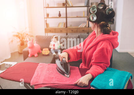 Mutter und Kind zusammen im Haushalt Bügeln engagiert. Hausfrau und Kind Hausaufgaben machen. Frau mit Kind im Wohnzimmer. Homemake Stockfoto