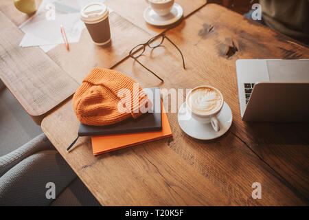 Ein Bild der modernen minimalistischen Tabelle mit einigen Getränken, Kleidung und Laptop. Schnittansicht Stockfoto