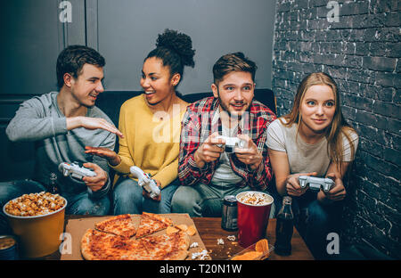 Ein Bild, in dem zwei Spieler mit niedriger sind - fünf auf einander, während die anderen beiden das Spiel spielen. Sie alle genießen die Zeit zusammen verbringen Stockfoto
