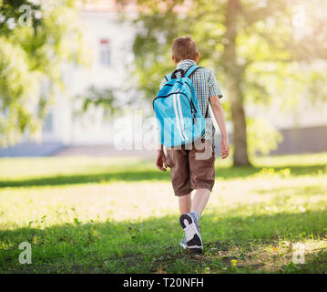 Junge mit Rucksack infront von einem Schulgebäude Stockfoto