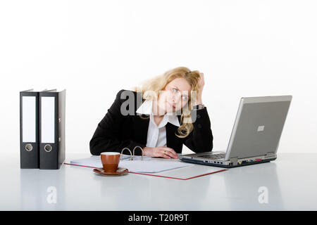 Eine Geschäftsfrau sitzt nachdenklich vor ihrem Laptop. Von einem weißen Hintergrund. Stockfoto