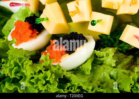 Käsespieße mit Trauben auf die Hälfte gekocht Eier mit lachstatar und Kaviar. Stockfoto