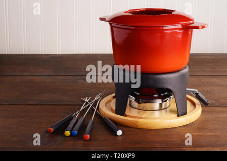 Red Gusseisen fondue Topf mit Spießen Stockfoto