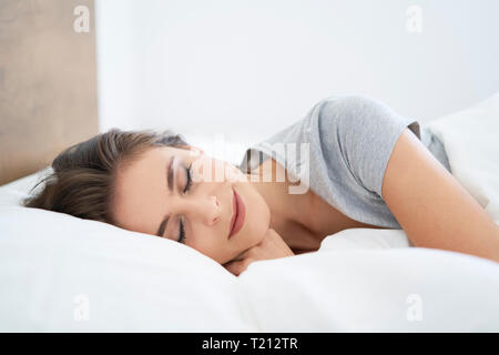 Junge Frau ruht auf dem Bett, mit geschlossenen Augen Stockfoto