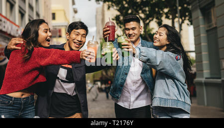 Fröhlicher junger Freunde toasten Getränke auf der Straße. Zwei asiatische paar Getränke genießen im Freien in der Stadt. Stockfoto