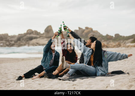 Vier asiatischen Freunden Bier Toasten auf dem Strand begeistert. Junge Menschen am Strand eine Party mit Getränken. Stockfoto