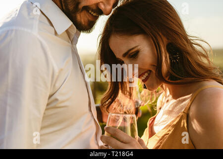 7/8-schuss ein glückliches Paar stehen zusammen mit einem Glas Wein. Verliebtes Paar teilen romantische Momente während eines Datums stehen im Freien. Stockfoto