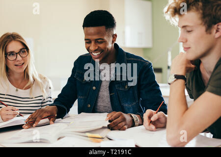 Vielfältige Gruppe von Studenten diskutieren auf Notizen. Glücklich und lächelnd Schüler studieren an der Bibliothek. Stockfoto