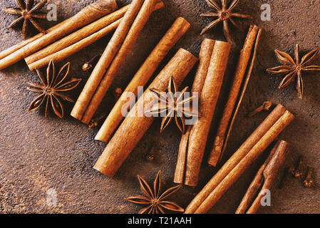 Mischung aus verschiedenen Gewürzen auf die texturierte braun Tabelle, Ansicht von oben Zusammensetzung Stockfoto