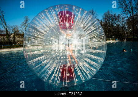 30. März 2019, Hessen, Frankfurt/Main: eine Frau Rollen in einem riesigen Wasserball über der Wasseroberfläche. Die open-air Swimming pool Saison in der Mainmetropole mit dem traditionellen Schwimmen im Hausen Freibad geöffnet. Foto: Andreas Arnold/dpa Stockfoto