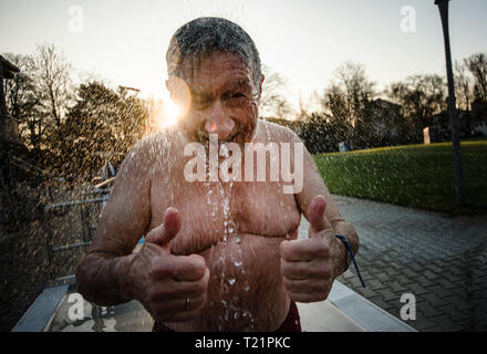 Frankfurt am Main, Deutschland. 30. März, 2019. Ein Mann steht unter der kalten Dusche mit seinem Daumen nach oben. Die open-air Swimming pool Saison in der Mainmetropole mit dem traditionellen Schwimmen im Hausen Freibad geöffnet. Foto: Andreas Arnold/dpa Quelle: dpa Picture alliance/Alamy leben Nachrichten Stockfoto