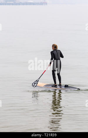 Branksome Dene, Poole, Dorset, Großbritannien. 30 Mär, 2019. UK Wetter: Diesig morgen Sonnenschein und kühler von spät, aber hört nicht auf Besucher Position am Meer in Branksome Dene. Frau paddleboarding. standup paddleboarder Standup Paddle boarder Credit: Carolyn Jenkins/Alamy leben Nachrichten Stockfoto