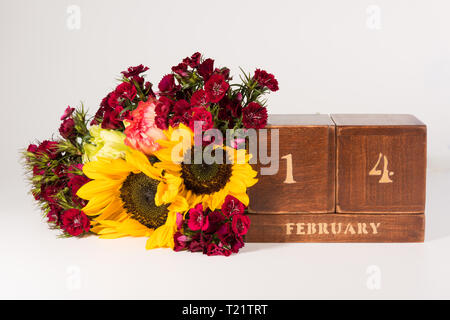 Happy Valentine's Day vintage Holz- Ewiger Kalender für Februar 14 isoliert auf weißem Hintergrund und ein Bündel von verschiedenen Blumen Stockfoto