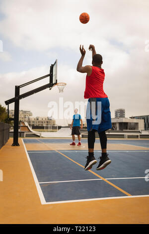 Basketball Spieler schießen, während ein anderer Spieler auf seine Schießen Stockfoto