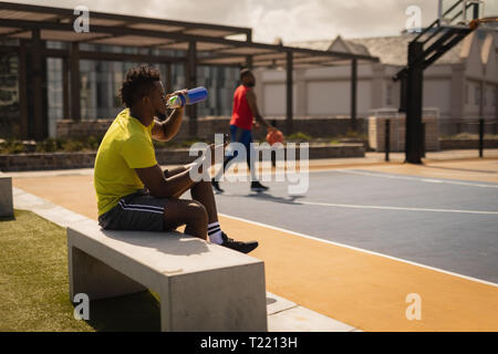 Basketball player Trinkwasser beim Entspannen am Basketballplatz Stockfoto