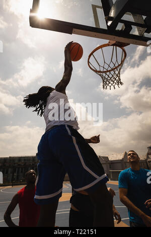 Afrikanische Basketballspieler springen einen Reifen zu zählen, während andere auf ihn suchen Stockfoto