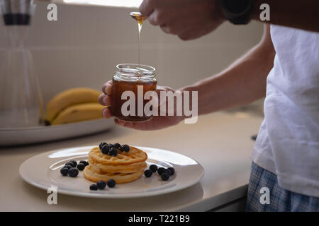 Mann Vorbereitung Waffel Frühstück in der Küche zu Hause. Stockfoto