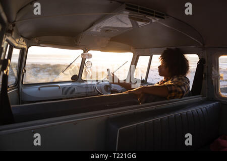 Mann mit Handy im Wohnmobil am Strand Stockfoto