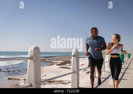 Junge Paare, die auf der Promenade in der Nähe von Strand Stockfoto