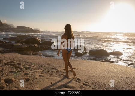 Schöne Frau zu Fuß am Strand an einem sonnigen Tag Stockfoto