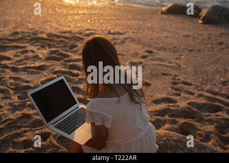Schöne Frau mit Laptop am Strand Stockfoto