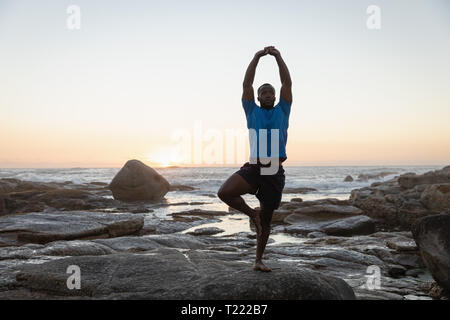 Mann tut Yoga am Strand Stockfoto