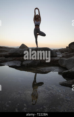 Frau Yoga auf Felsen am Strand Stockfoto