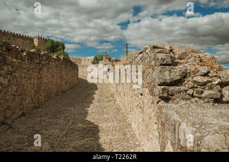 Gasse mit Pflaster und Mauern aus Stein am Hang in Richtung Schloss von Trujillo. Geburtsort Stadt der Eroberer Francisco Pizarro in Spanien. Stockfoto