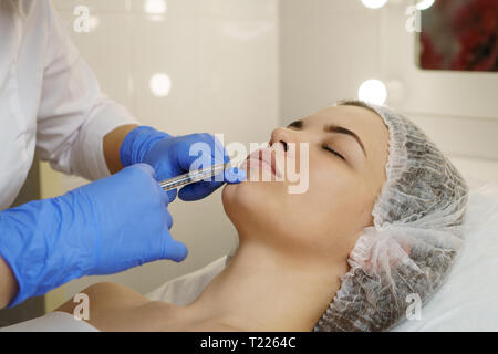 Ästhetische Kosmetologie. Facelift in Spa Salon. Kosmetikerin macht Injektionen Mädchen in der Lippen. Glättung von Falten nachahmen. Close-ups Stockfoto