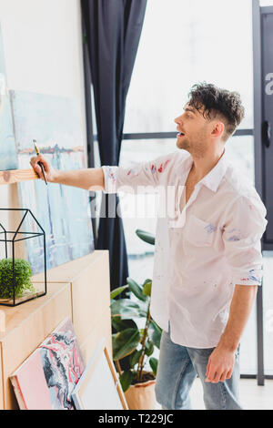 Inspiriert Künstler in weißem T-Shirt stand vor der Abbildung in der Malerei studio Stockfoto