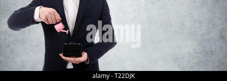 Mann hält pink Gießkanne und Aktentasche, Small Business Support Konzept, Bild auf Beton Wand Hintergrund Stockfoto