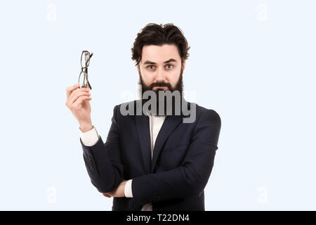 Bärtiger Mann mit Brille für die Augen in der Hand, Bild auf einem blauen Hintergrund Stockfoto