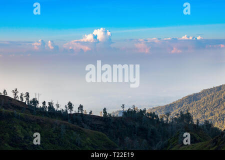 Luftbild von den Hängen des Ijen Vulkans komplexe Unter einem blauen Himmel mit cumulus Wolken bei Sonnenaufgang. Java, Indonesien Stockfoto