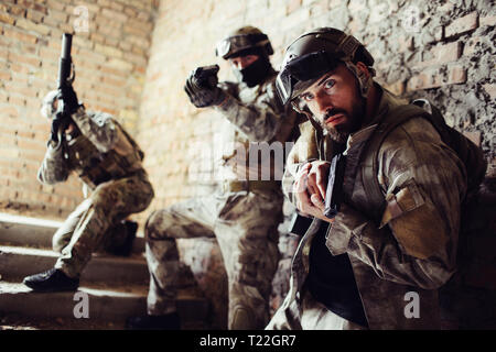 Drei Krieger stehen auf Treppen und posieren. Mann in einem vorderen Sucht gerade nach vorn und Halten der Waffe. Der zweite Typ ist der Ziel Geraden fo Stockfoto