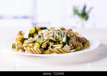 Rezept Schritt für Schritt Fusilli mit Zucchini auf weißem Porzellan Teller mit roten Blumen auf Weiß im Hintergrund Stockfoto