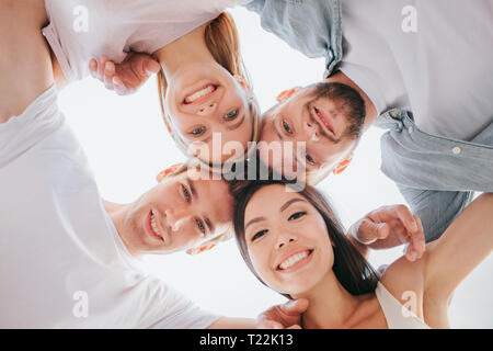 Schönes Bild von positiven Teens ihre Köpfe halten nahe beieinander, auf Kamera. Sie lächeln. Es gibt zwei Jungen und zwei Mädchen. Stockfoto