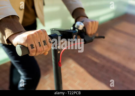 Hand der tätowierten Mann, Lenker von E-Scooter, close-up Stockfoto