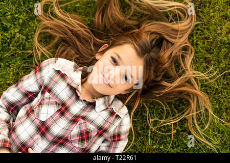 Porträt der lächelnde Mädchen mit langen Haaren liegen auf einer Wiese Stockfoto