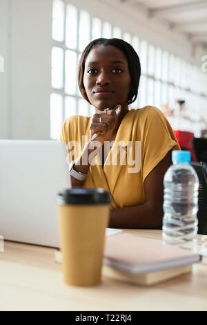 Portrait von selbstbewussten jungen Frau am Schreibtisch im Büro Stockfoto