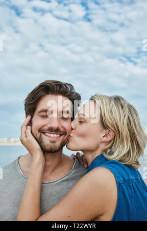 Glückliches junges Paar küssen am Strand Stockfoto