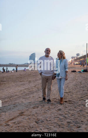 Spanien, Barcelona, Senior paar Hand in Hand am Strand bei Sonnenuntergang Stockfoto