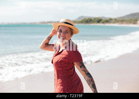 Spanien, Mallorca, Porträt der glückliche junge Frau mit Tattoos auf den Strand Stockfoto