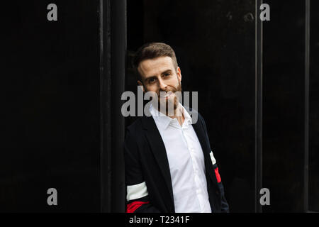 Portrait ofsmiling stilvolle Geschäftsmann gegen eine Wand gelehnt Stockfoto